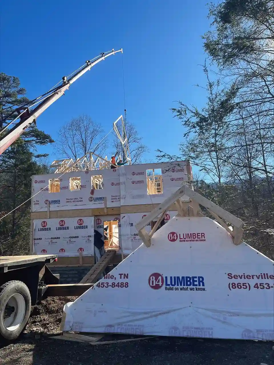 Crane setting roof trusses on a wrapped two-story frame